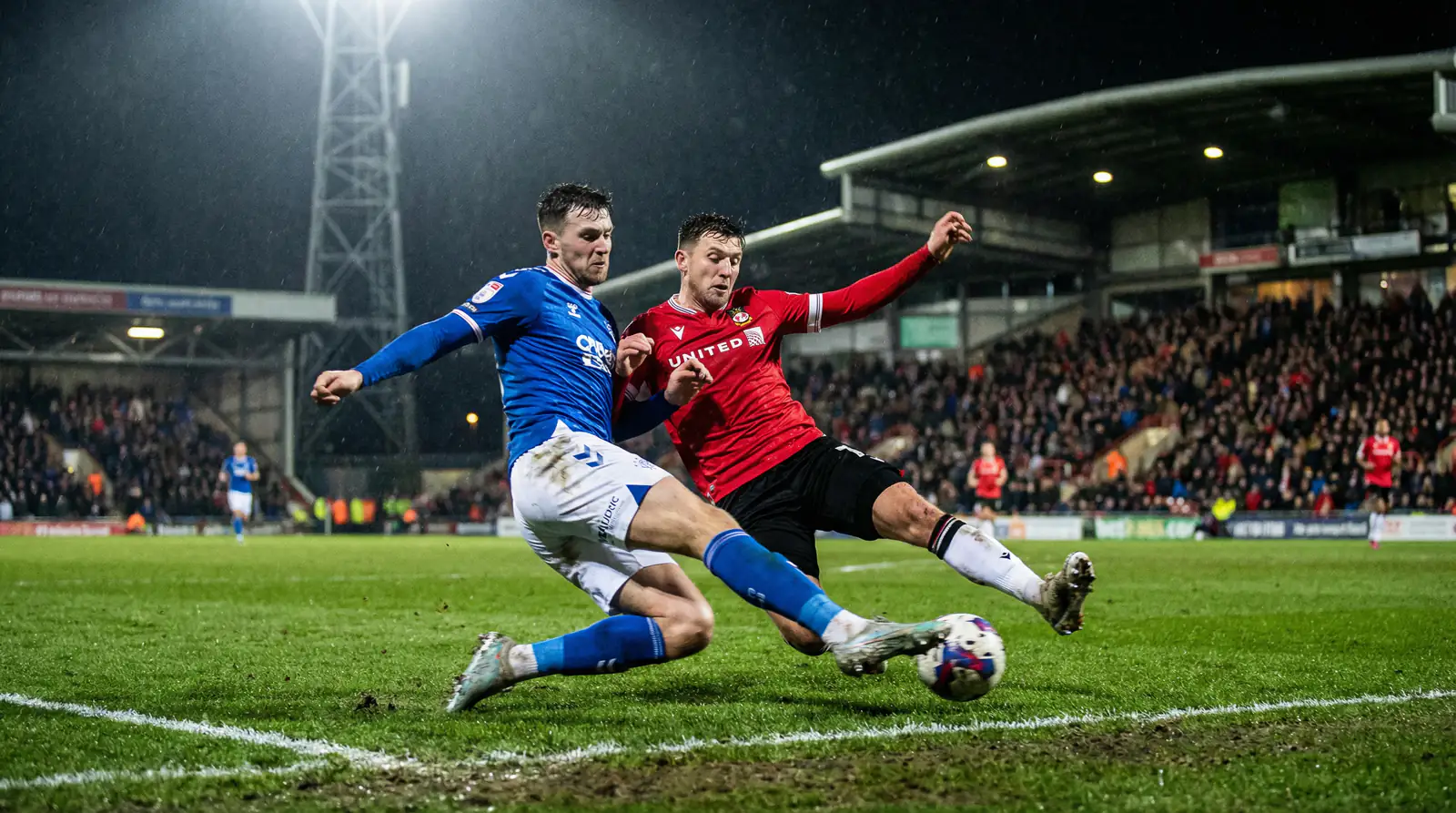 Fotbalisté na trávníku při skupinovém zápase pod umělým osvětlením